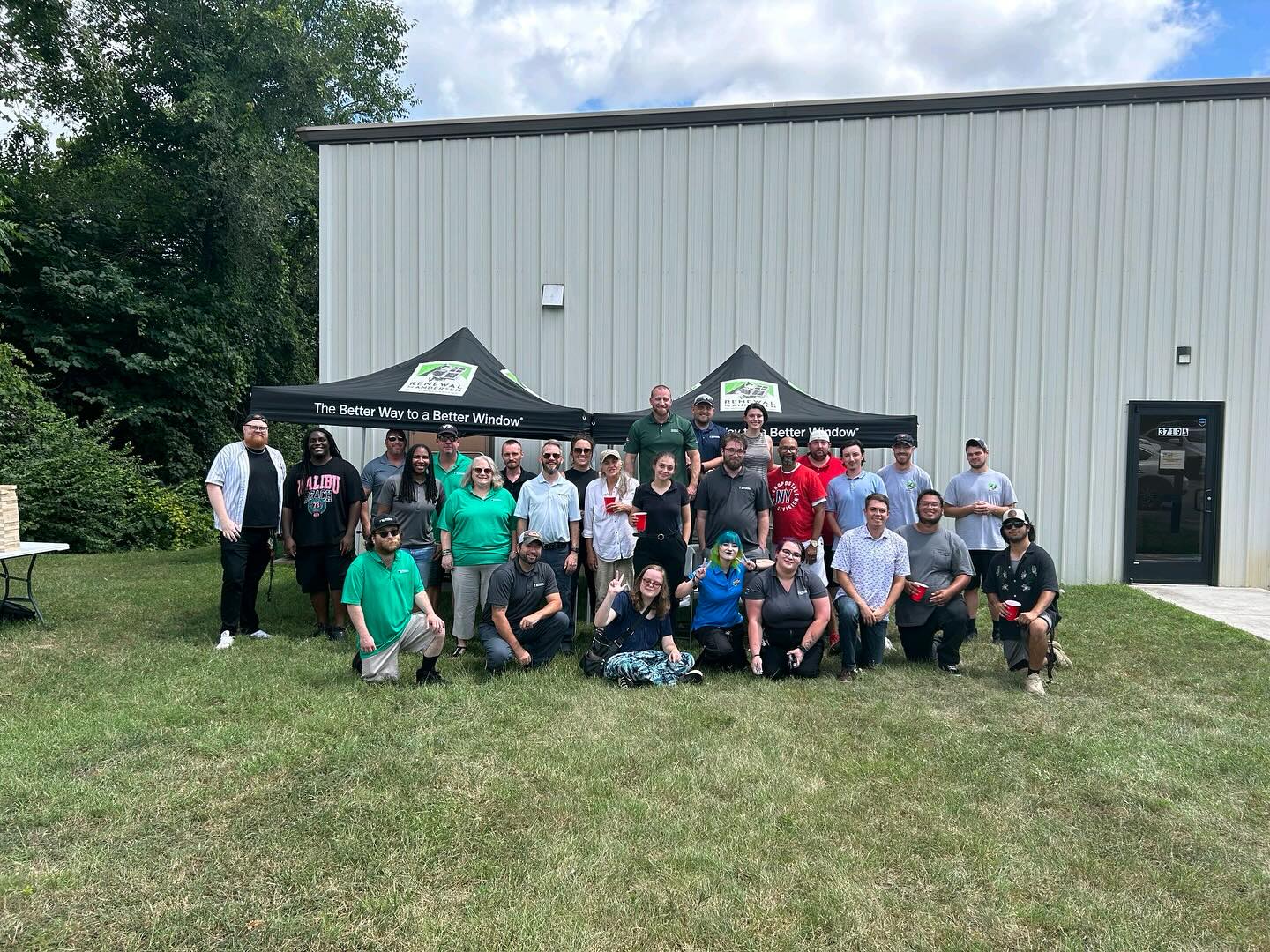 Group of people in front of Renewal by Andersen tents by a building