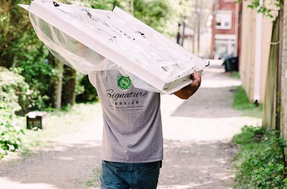 Renewal by Andersen employee carrying a window