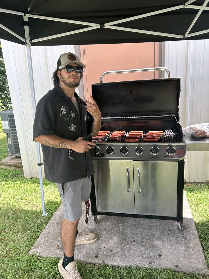 Man giving a peace sign next to a grill