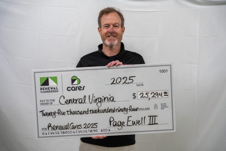 Smiling man holding a large check for Renewal Cares