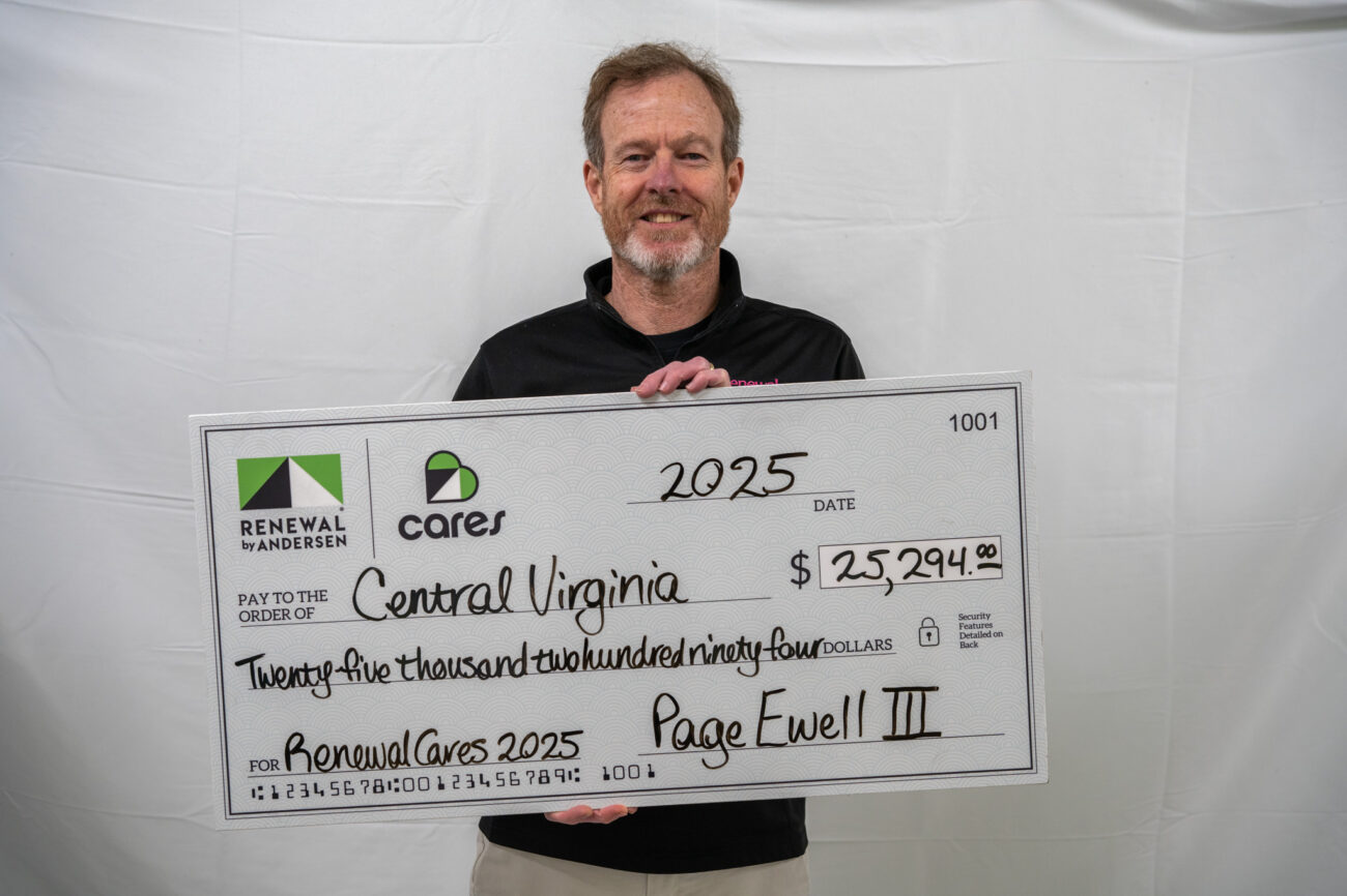 Smiling man holding a large check for Renewal Cares
