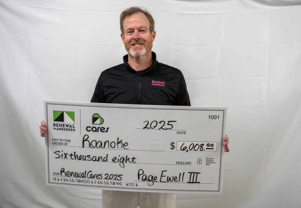 Smiling man holding a large check for Renewal Cares
