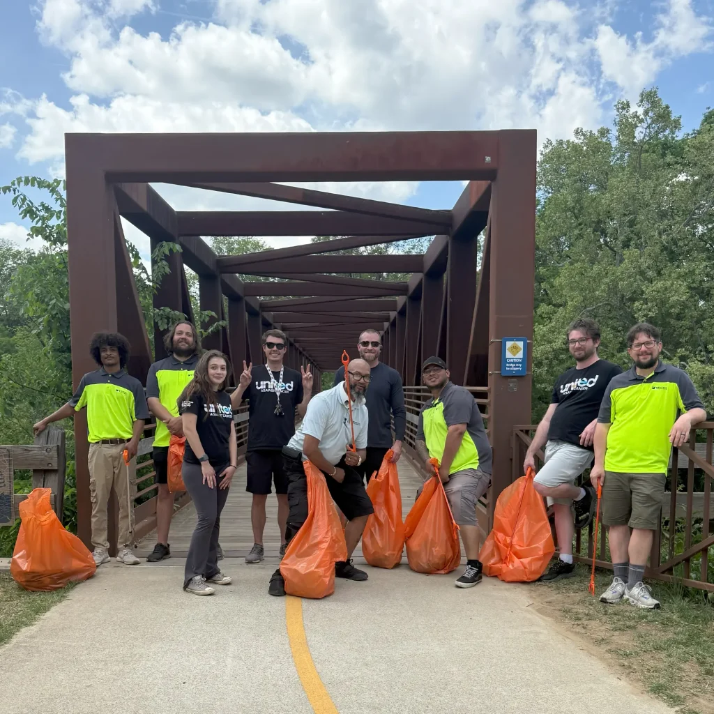 Group of people with trash bags in front of a bridge