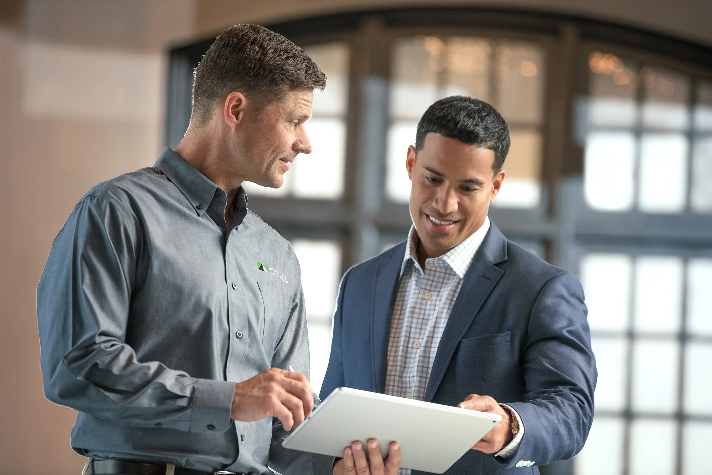 Two men talking while looking at a tablet