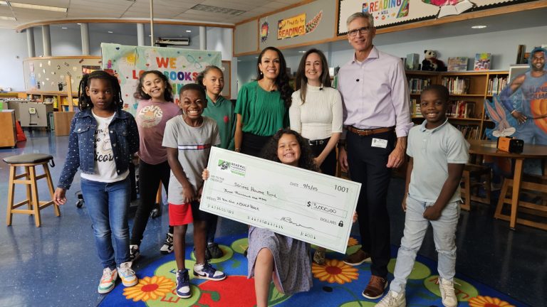 Group of Renewal by Andersen employees and children smiling with a large check