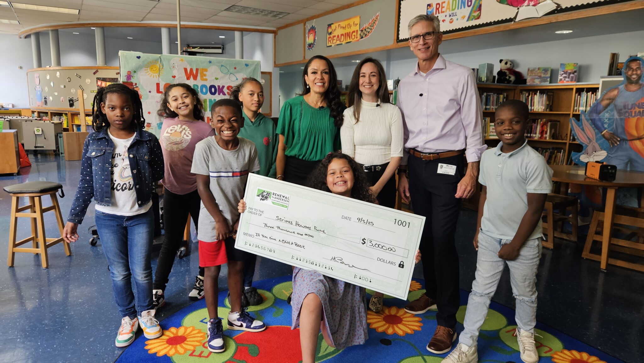 Group of Renewal by Andersen employees and children smiling with a large check