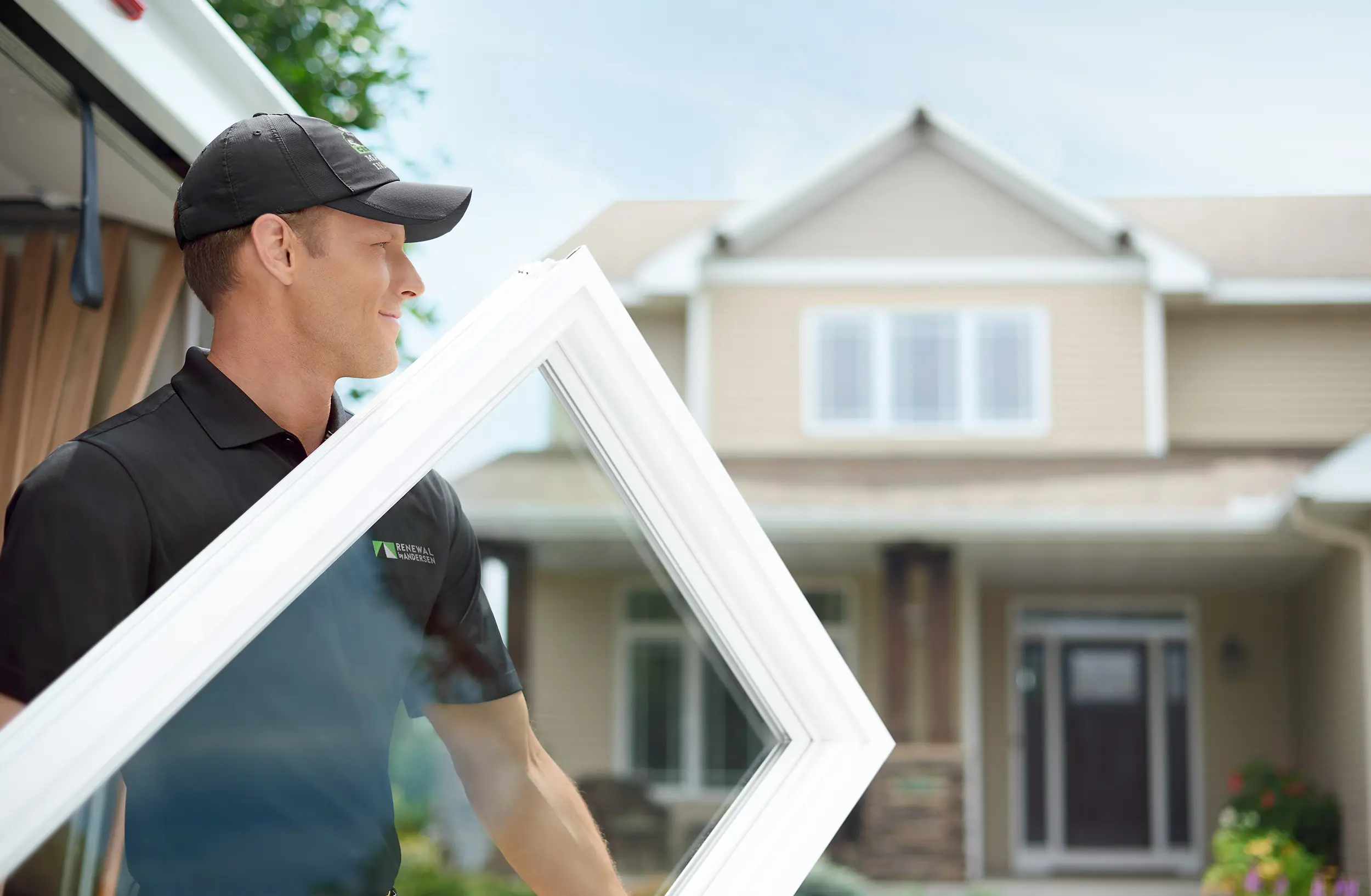 Man holding white window in front of a house
