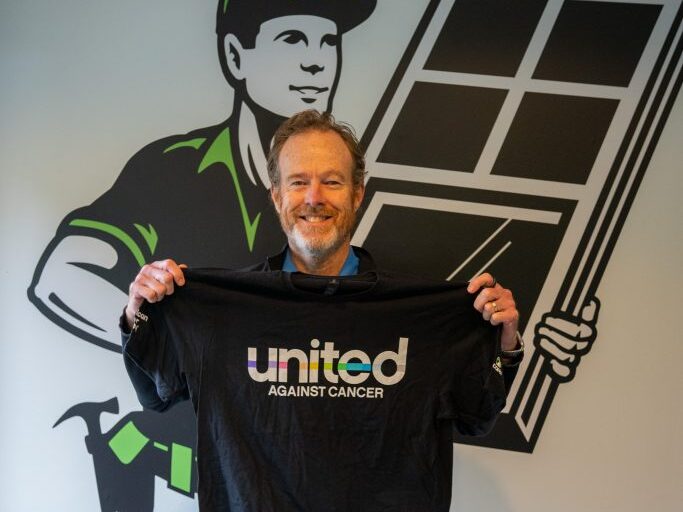 Page Ewell III holding his United Against Cancer shirt up