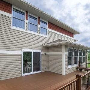 Tan house with red stripe and white windows and a back deck