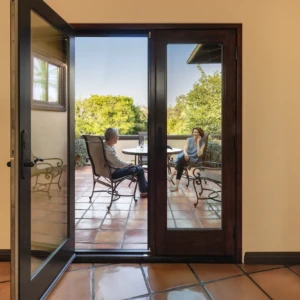 Glass doorway showing two people sitting at a patio table outdoors